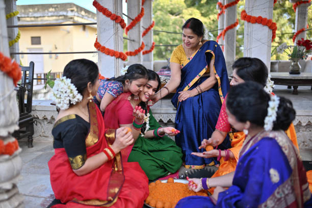 Cute girl embracing her mother while she makes ladoos during a traditional function in a Palace in Rajasthan