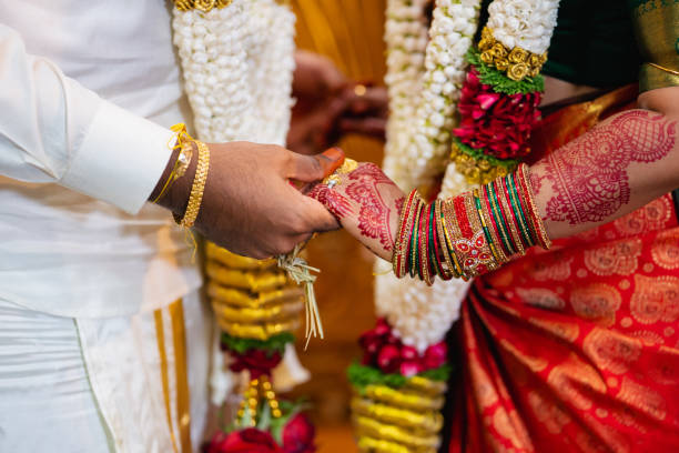 Close up of groom hand holding brides hand at an Indian Wedding. Concept of marriage, partnership, commitment.